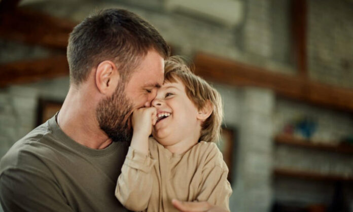 Un père souriant tenant son enfant, symbole de la paternité heureuse.